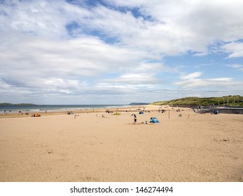 A busy beach in northern ireland with blue skies over head