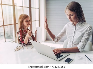 I'm busy! Beautiful young woman is working at home with her little cute daughter nearby. Don't have enough time for child.
