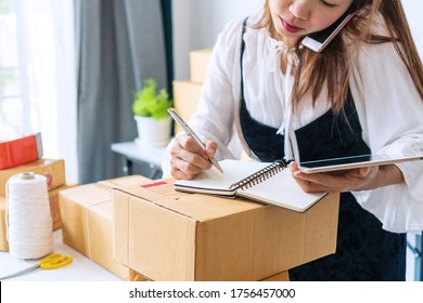 Busy Business Owner Multitasking With Talking On The Phone With Customer, Take Note On Notebook And Checking Stock Balance From Tablet. Online Selling, E-commerce Concept.