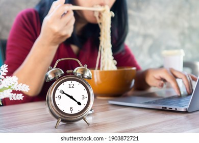 Busy Business Woman Having Lunch Late Eating Noodle And Working At Office With Alarm Clock On Desk 