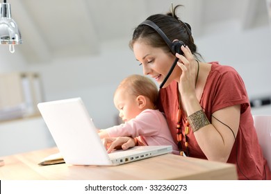 Busy businesswoman working with baby on lap