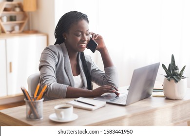 Busy Businesswoman Working At Desk In Office, Talking On Cellphone And Typing At Laptop, Copy Space
