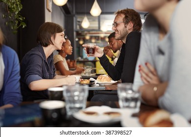 Busy Cafe With A Young Couple Smiling At Each Other