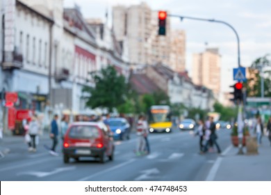 Busy city street with people and cars in motion blur on crosswalk. Traffic lights regulation.
