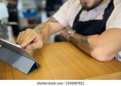 Busy Coffee Shop Worker Using Tablet To Calculate A Receipt