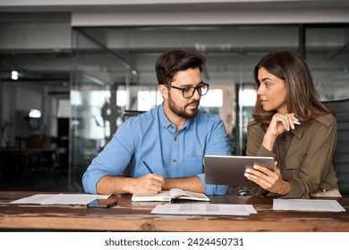 Busy colleagues working with digital tablet talking in office. Professional partners having conversation at meeting. Female executive manager showing work plan using tab helping new employee. - Powered by Shutterstock