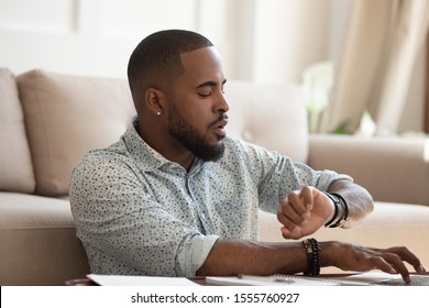 Busy Concentrated African American Male Working On Laptop At Home Look At Hand Watch Checking Time, Focused Biracial Student Typing Studying On Computer Worried Not Miss Appointment Or Deadline