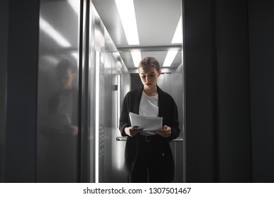 Busy Concentrated Office Worker Is Reading The Documents While The Elevator Door Is Closing.