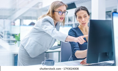 In the Busy Corporate Office: Female Manager Explains Task to Businesswoman who Works on Desktop Computer. Businesspeople an Working with Clients, Having Discussions and Analysing Statistics