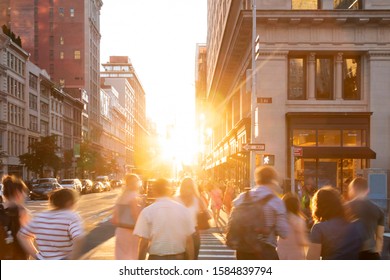 Busy crowds of people walking down the sidewalk on 23rd Street in New York City with bright sunlight shining in the background