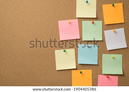 Busy day at work concept. Photo of lot of colorful notepaper attached with pins to the wooden board