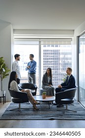 Busy diverse professional team business people workers talking in modern corporate office lobby. International coworkers group having teamwork conversation together at work meeting. Vertical shot - Shutterstock ID 2346440505