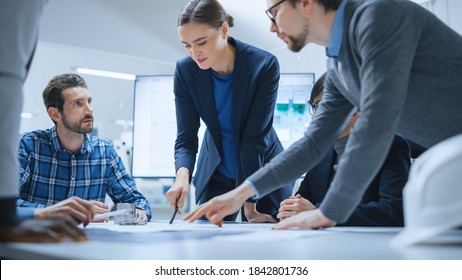 Busy Diverse Team of Computer Engineers and Specialists Gather Around Conference Table, They Discuss Project Drafts and Blueprints, Find Problem Solutions. Industrial Technology Factory Meeting Room