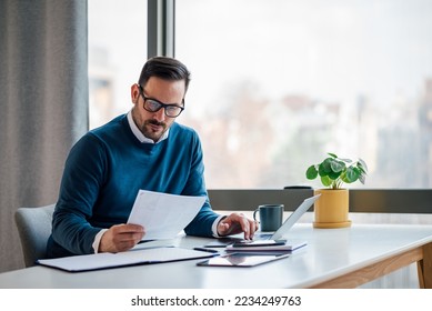 Busy elegant bearded adult company director, checking the company finances, at the office. - Shutterstock ID 2234249763