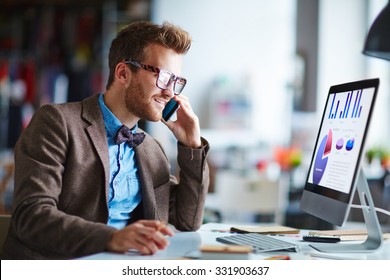 Busy Employee Speaking On The Phone While Looking At Computer Screen