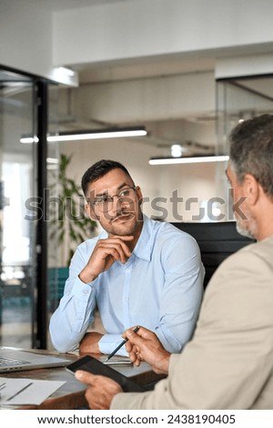 Busy executive team of two business men discussing digital finance banking project strategy working in office with laptop and tablet. Financial advisor consulting partner at meeting. Vertical