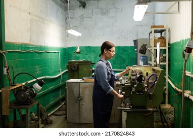 Busy Experienced Middle-aged Woman In Protective Eyewear Punching Metal On Manual Lathe Machine At Factory