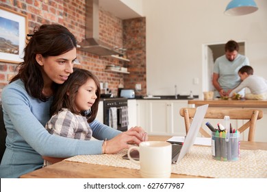 Busy Family Home With Mother Working As Father Prepares Meal