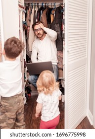 Busy Father Trying To Find A Quiet Place In A Wardrobe  To Hide From Children For A Work At The Laptop. Stay Home Concept. Quarantine. Freelancer.