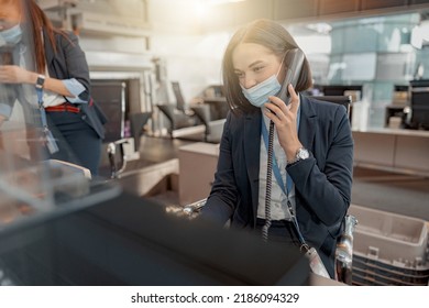 Busy Female Airport Employee In Mask Sitting At The Check-in Desk