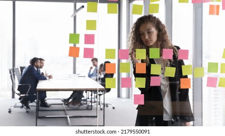 Busy Focused Businesswoman Writing Memos On Paper Notes On Glass Board, Preparing Presentation For Team Meeting, Planning Business Process, Schedule. Through Glass View