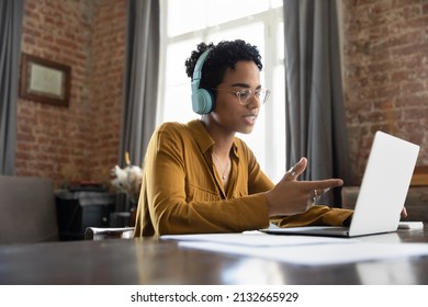 Busy Focused Stylish Black Worker In Headphones Talking To Client On Video Call At Paper Documents On Work Table. College Student Watching Learning Webinar On Internet, Studying Online