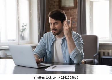 Busy Freelance Business Professional Man Listening Audio Message On Cellphone At Home Workplace. Project Leader, Remote Employee Engaged In Multitasking, Making Phone Call On Speaker, Using Laptop