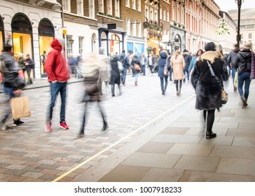 A Busy High Street With Anonymous Crowds Of Shoppers With Shopping Bags