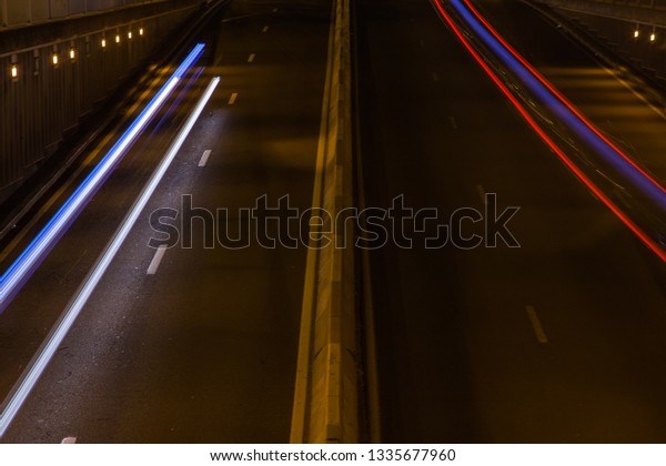 A busy\
highway road with cars returning home from work at night, cars pass\
by as rays of light due to long\
exposure