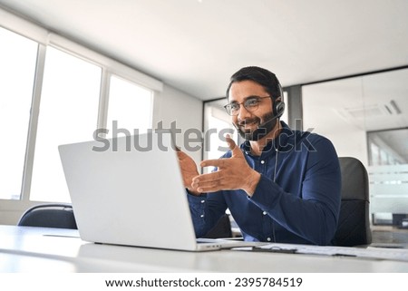 Busy Indian call center agent wearing headset talking to client working in customer support office. Professional contract service operator telemarketing representative using laptop having conversation