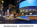 Busy intersection with cars, buses and taxis driving on 42nd Street through Times Square in New York City at night