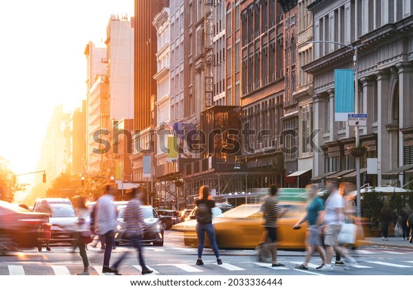 Busy intersection with crowds of people and\
cars on 5th Avenue in Manhattan New York City with sunset light\
shining behind the\
buildings