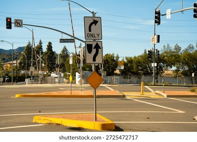 A busy intersection features traffic lights, railroad crossing gates, and signs indicating lane directions and restrictions