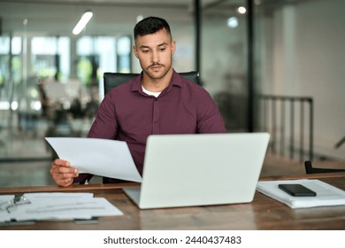 Busy Latin lawyer checking documents working at laptop in office. Serious business man legal expert attorney reading law paper company file invoice overview looking at computer at workplace. - Powered by Shutterstock - Get 15% off with code: PIKWIZARD15