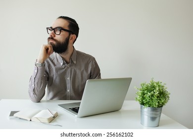 Busy Man With Beard In Glasses Thinking Over Laptop With Smartphone On The Table