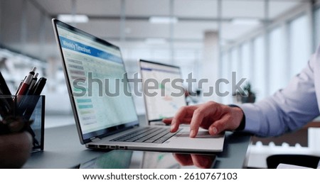 Busy Man In Office Using Computer To Track Weekly Schedule.