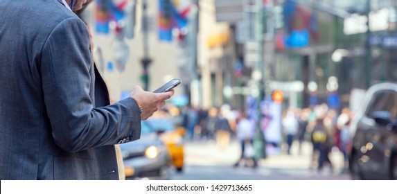 Busy man in suit checking his mobile phone. New York, Wall street. Blur crowded street, banner, copy space