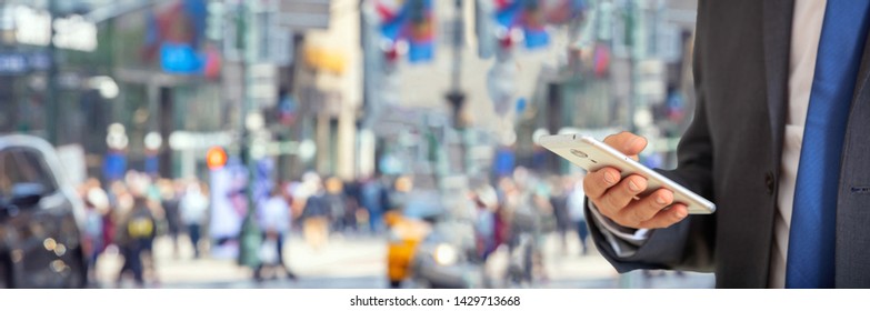 Busy man in suit checking his mobile phone. New York, Wall street. Blur crowded street, banner, copy space - Powered by Shutterstock