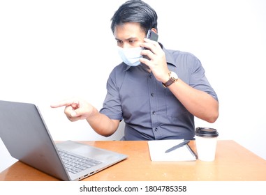 A Busy Man Wearing Mask Obeying Covid-19 SOP, Talking On The Phone With His Client During Working Hours In The Office.