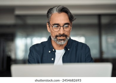 Busy mature business man, middle aged professional executive, older entrepreneur investor wearing glasses looking at laptop computer thinking on financial market working online in office. Close up. - Powered by Shutterstock