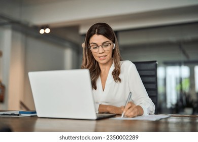 Busy mature business woman corporate leader, company team leader executive, hr manager having hybrid conference call meeting or remote online job interview on laptop computer working in office. - Powered by Shutterstock