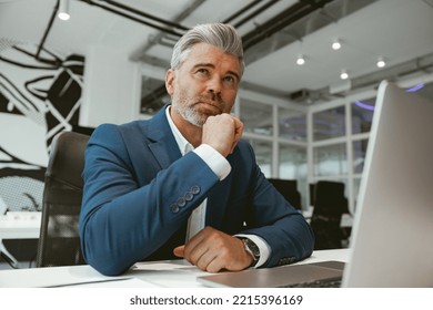 Busy Mature Businessman Working With Laptop While Sitting In Modern Coworking