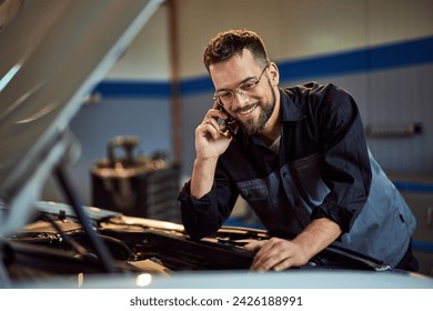 A busy mechanic man making a phone call while working at his garage. - Powered by Shutterstock