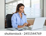 Busy middle aged female support service operator talking to customer sitting at desk. Happy mature woman professional call contact center agent wearing headset working in business office using laptop.