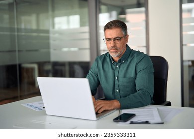 Busy middle aged professional business man executive investor using computer working at desk. Male manager expert looking at laptop thinking on online finance market analysis, elearning in office. - Powered by Shutterstock