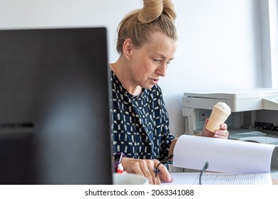 A Busy Middle-aged Office Woman Eats Ice Cream At Her Workplace Without Interrupting Work