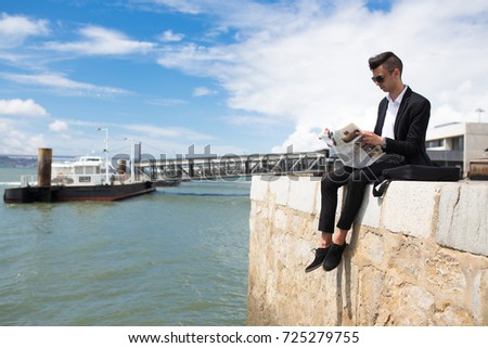 Busy modern student resting with newspaper on dock