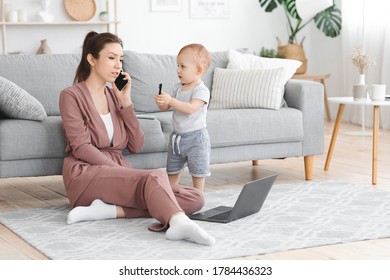 Busy Mom Answering Phone While Taking Care About Baby At Home, Sitting On Floor In Living Room With Laptop, Working Remotely