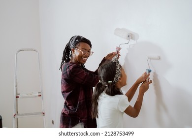 Busy mom spends time with cheerful daughter, engages her to help, together they painting the walls of the apartment under renovation, apply white paint with rollers - Powered by Shutterstock