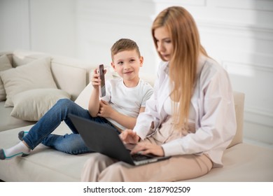 A Busy Mom Works At A Computer. Son Shows Funny Videos To Mom.